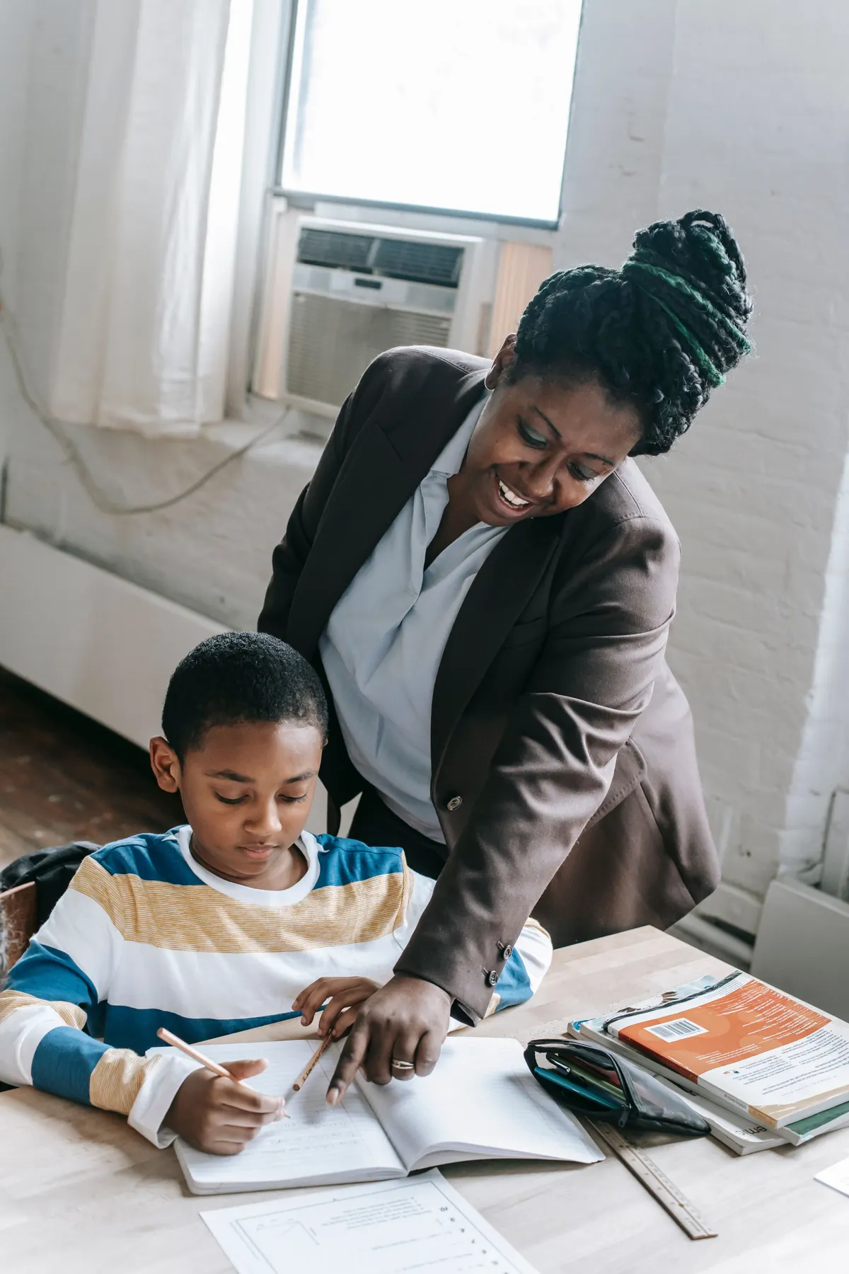 Une enseignante aide un élève penché sur son cahier